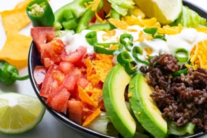 Low Carb Ernährung Grundlagen: Teller mit gebratenem Lachs, Brokkoli und Avocado auf einem hellen Holztisch