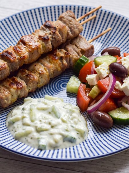 Souvlaki low carb: gegrillte griechische Fleischspieße mit Tzatziki und Bauernsalat auf einem Teller
